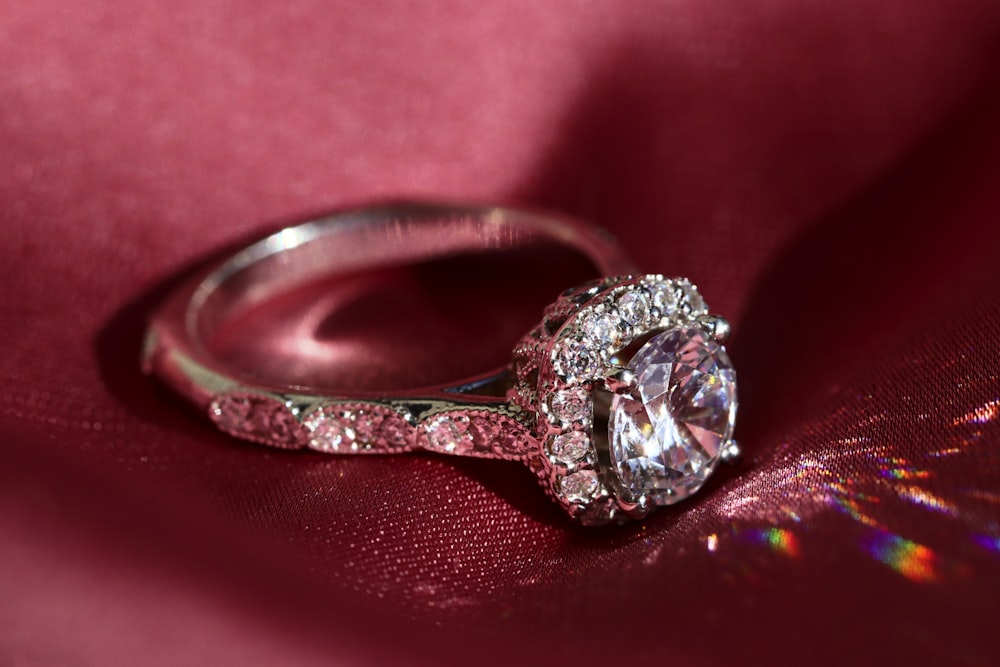 silver diamond ring on red textile