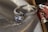 A sparkling diamond ring displayed on a fabric background with a soft, shimmering texture. The ring has a large central gemstone surrounded by smaller diamonds set along the band. The fabric underneath catches the light, adding a luxurious and elegant atmosphere.