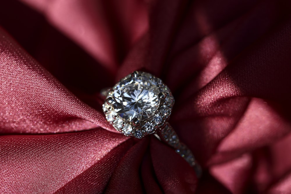 silver diamond ring on red textile