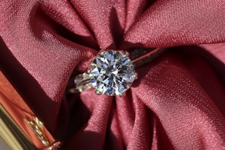 silver diamond ring on red textile