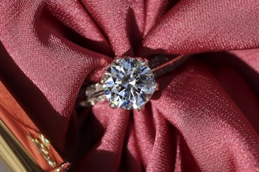 silver diamond ring on red textile