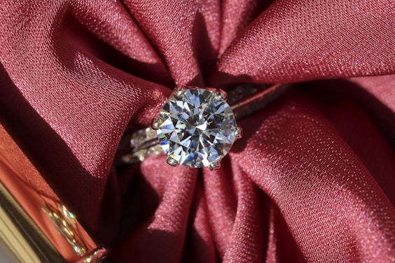 silver diamond ring on red textile