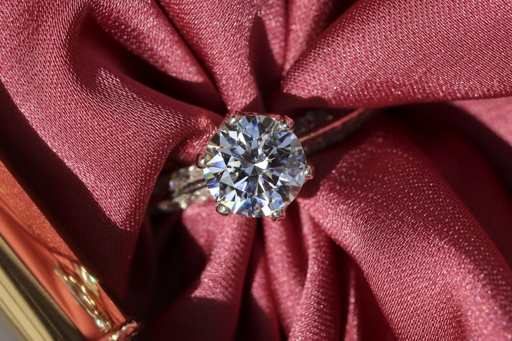 anel de diamante de prata no têxtil vermelho