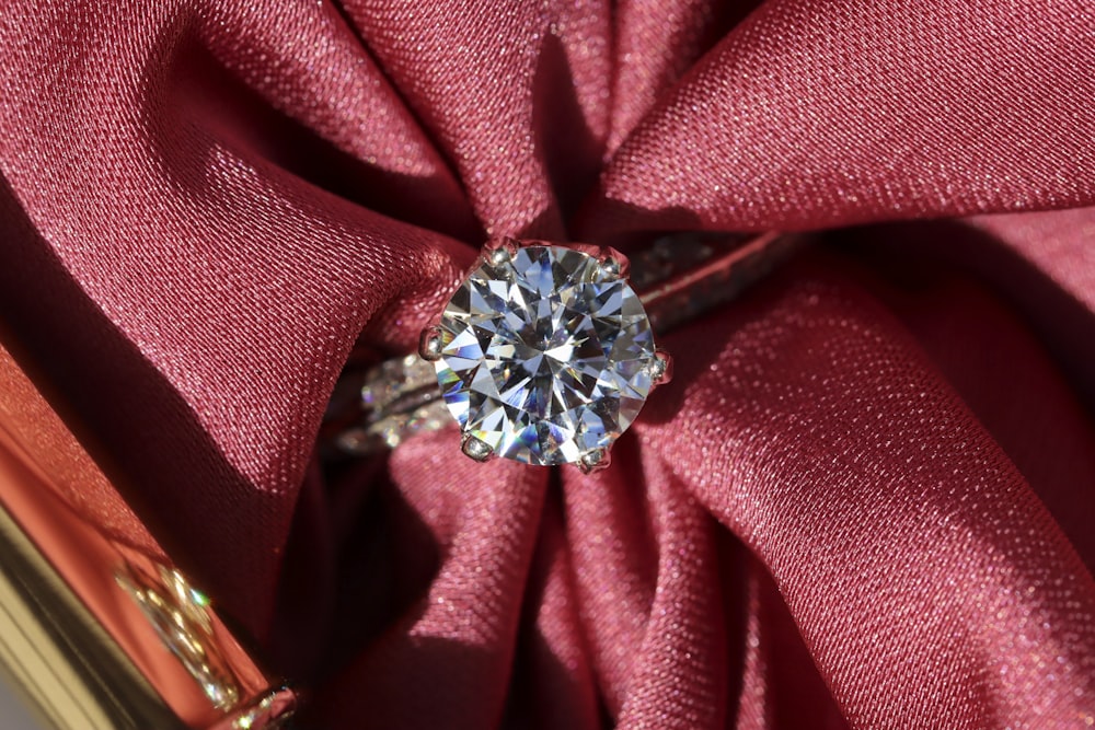 silver diamond ring on red textile