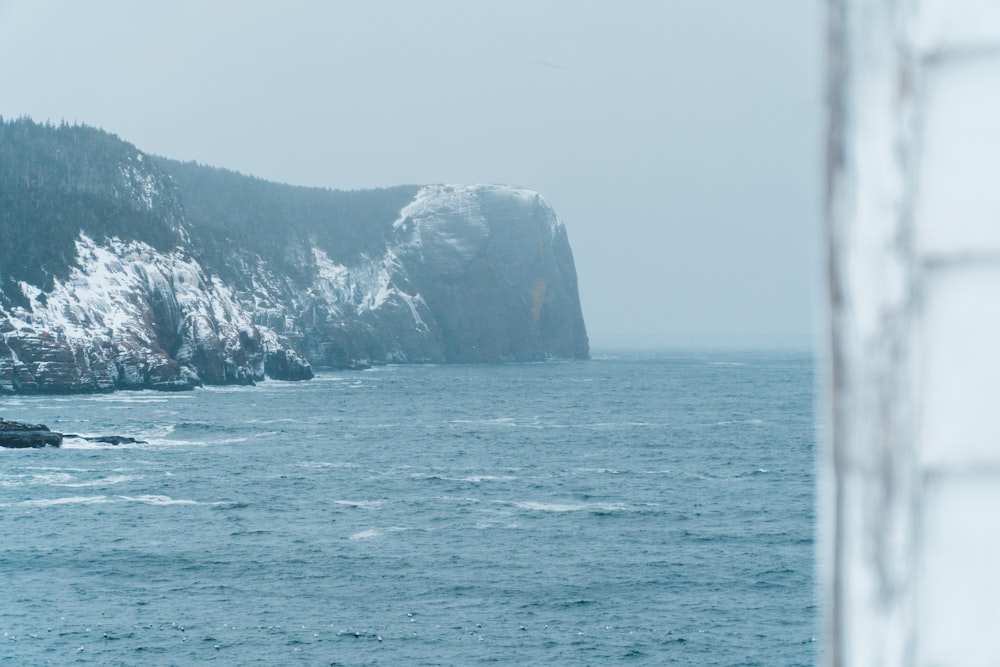 formação rochosa cinza e preta no mar durante o dia