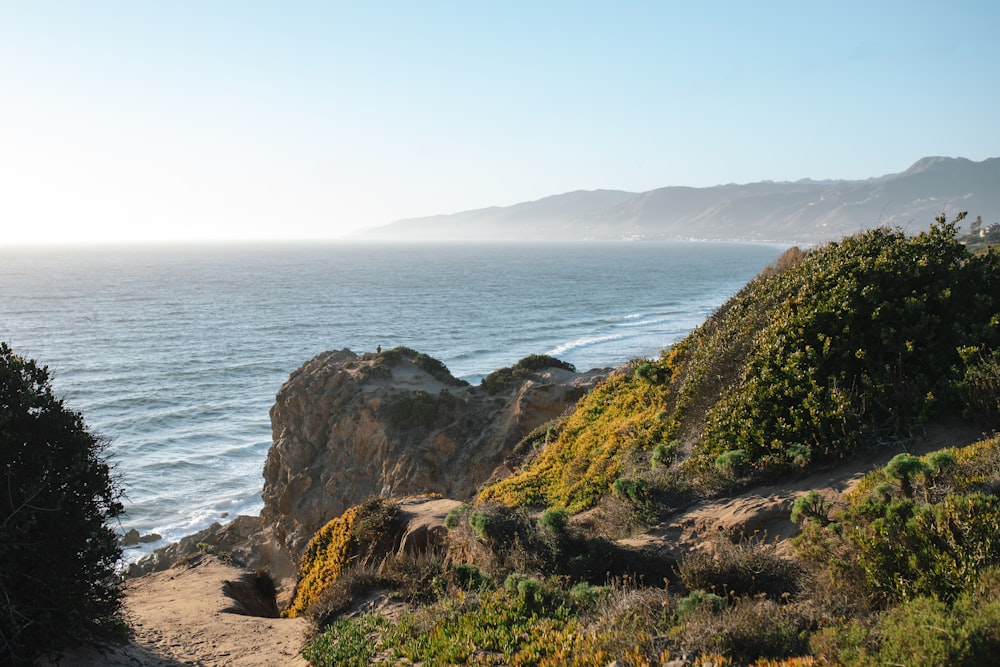 brown rocky mountain beside sea during daytime