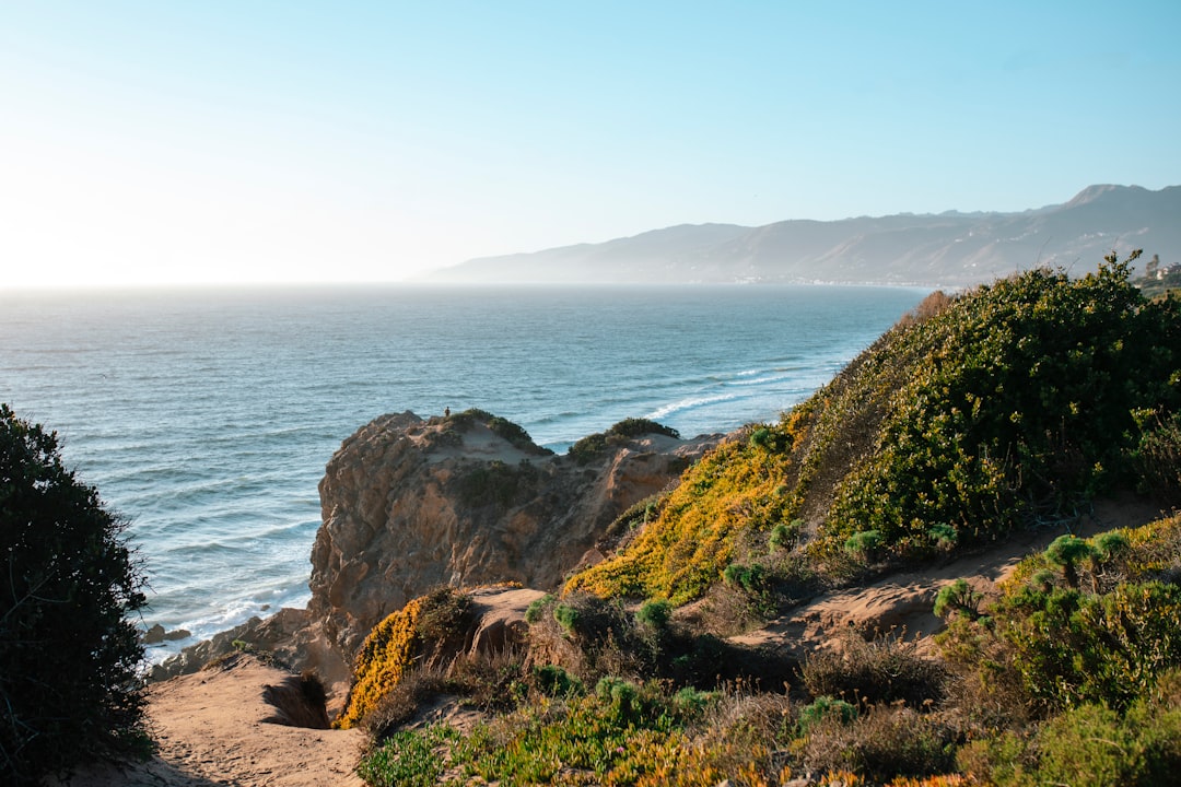 brown rocky mountain beside sea during daytime