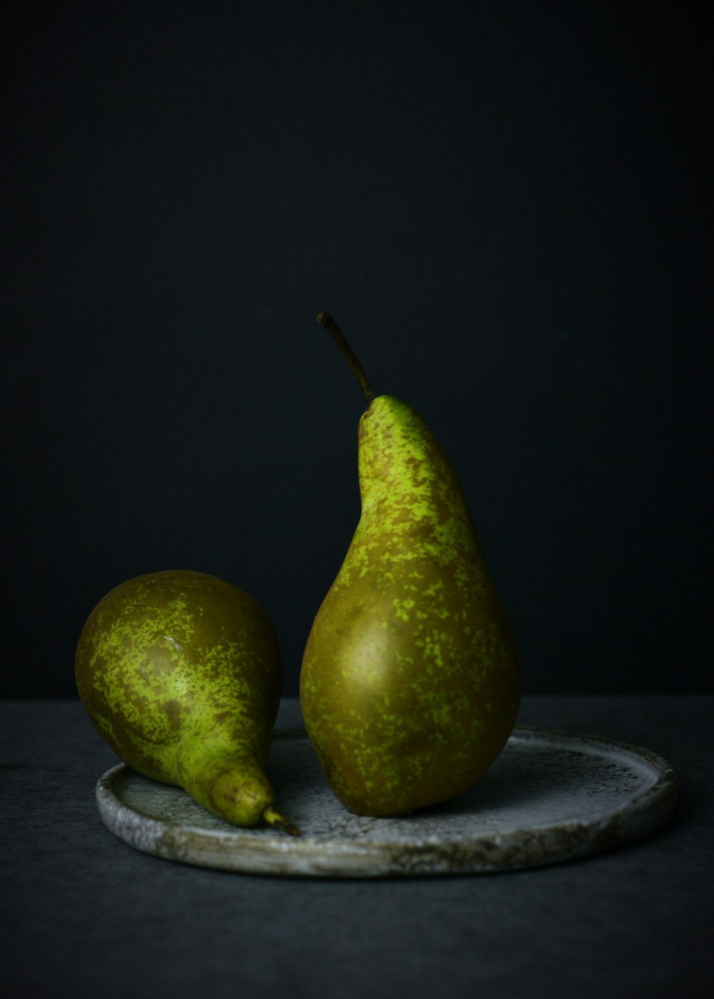 two green pear fruit on black round plate