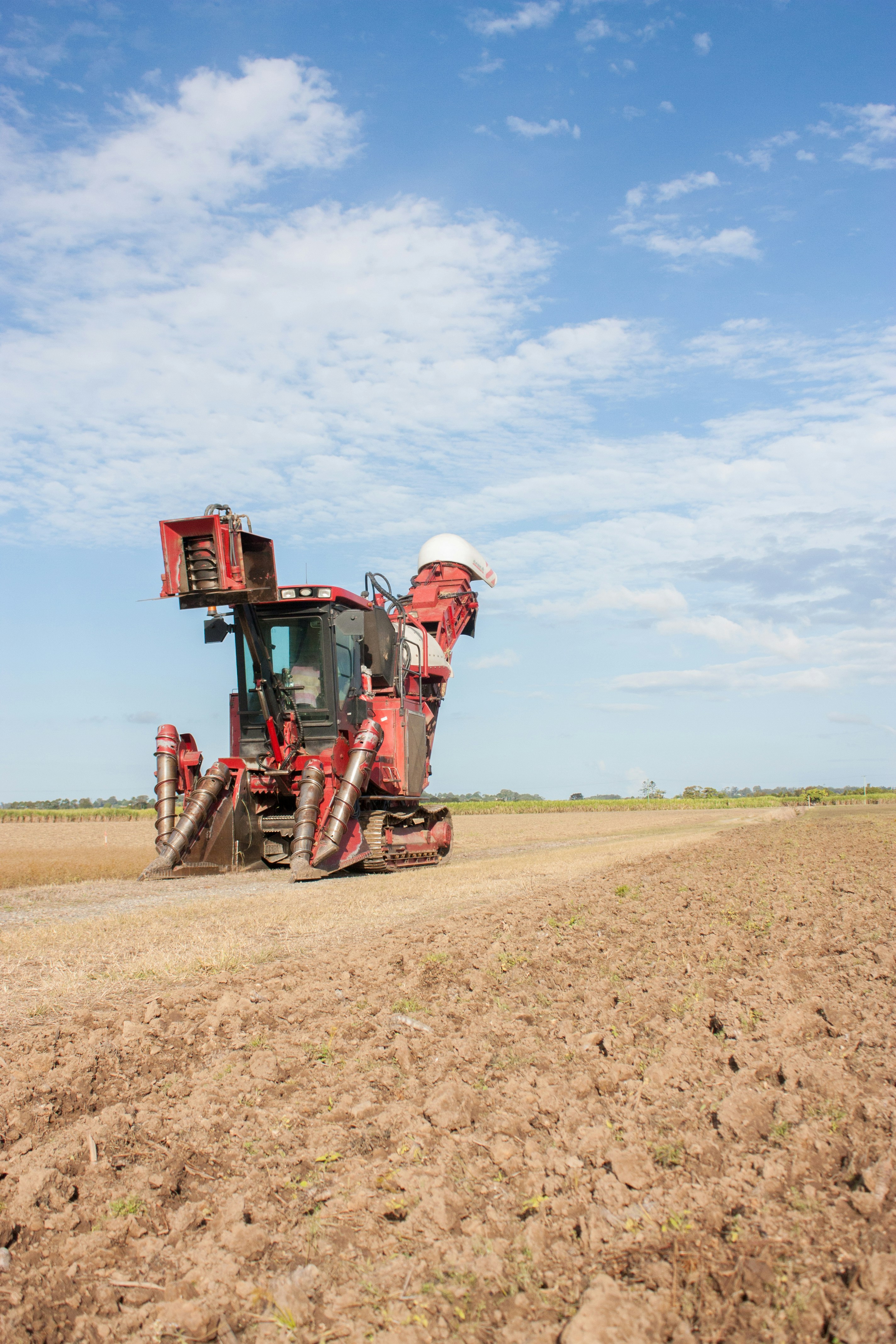 man in red and white long sleeve shirt and pants riding red tractor on brown field