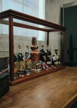 Close-up of a distiller proudly holding a certification plaque in a professional distillery setting.