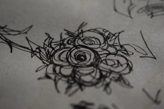 An artist's hand sketching a detailed floral design with colored pencils.