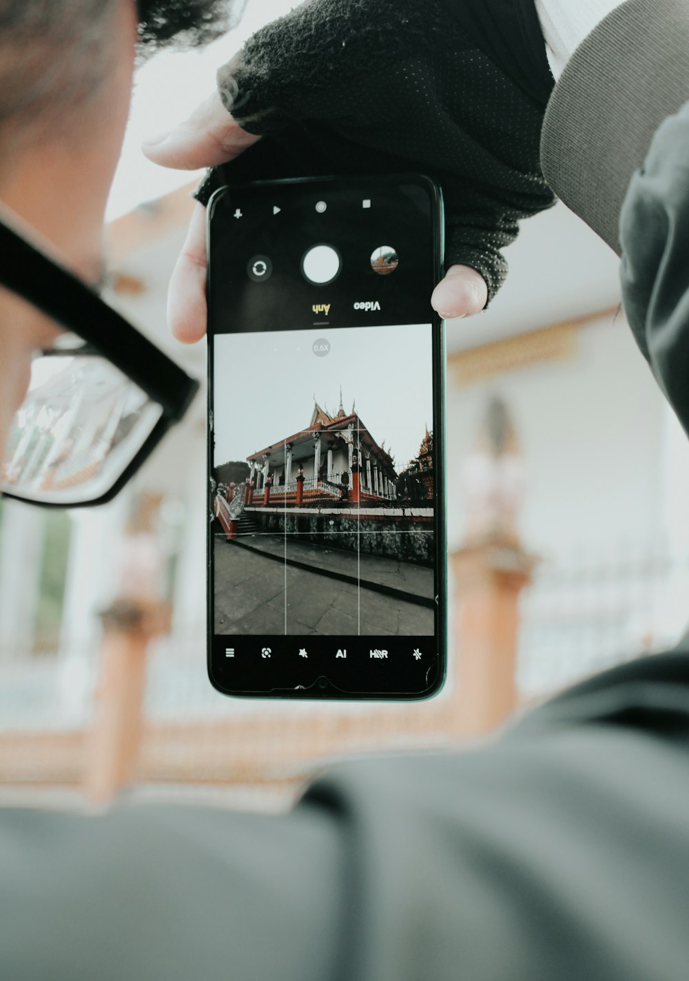 pessoa segurando iphone 5 preto tirando foto do edifício marrom