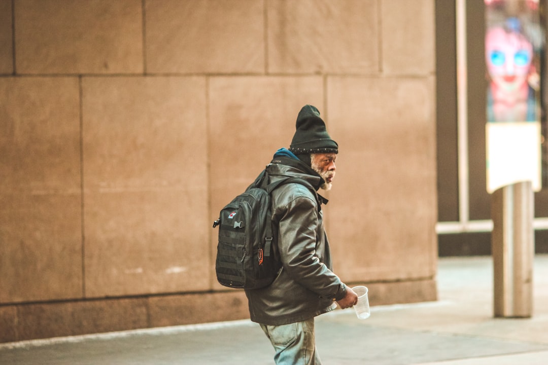 man in black jacket and gray pants walking on sidewalk during daytime