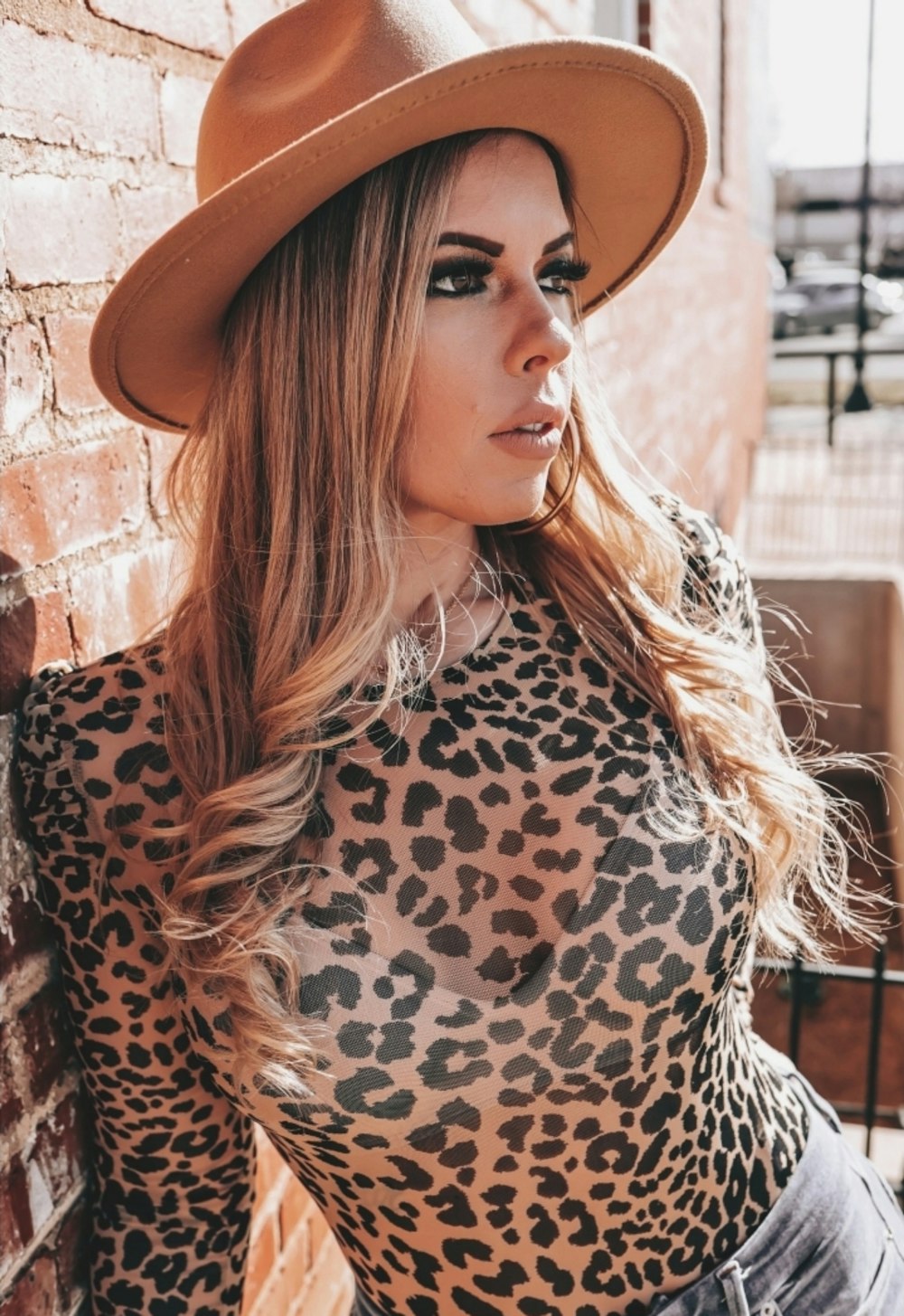 woman in brown and black leopard print shirt wearing brown cowboy hat