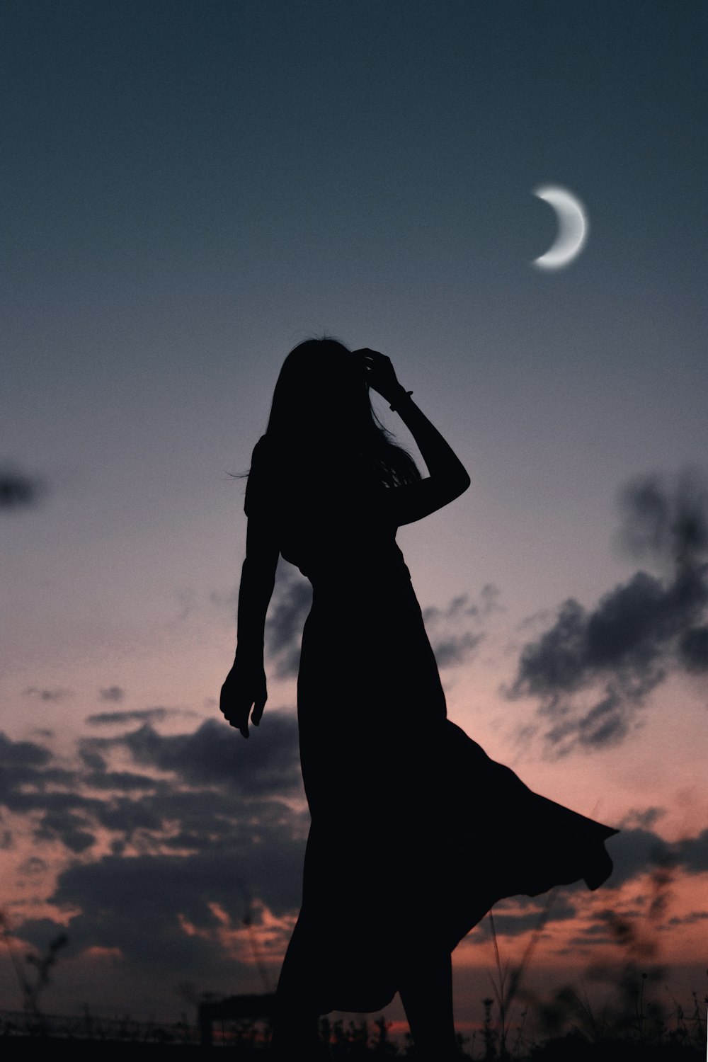 silhouette of woman standing under white clouds during daytime