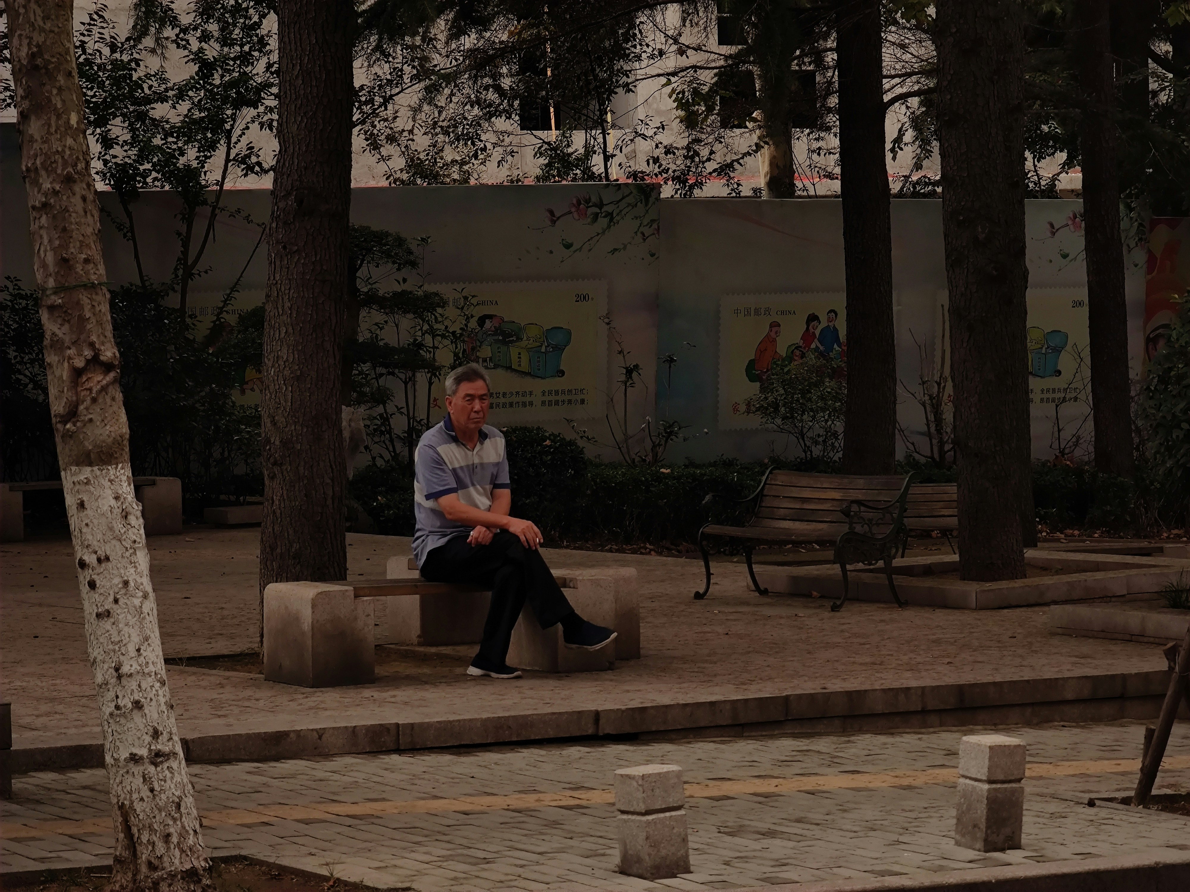 Old man playing chess alone in park, the other side of board empty, concentrated expression