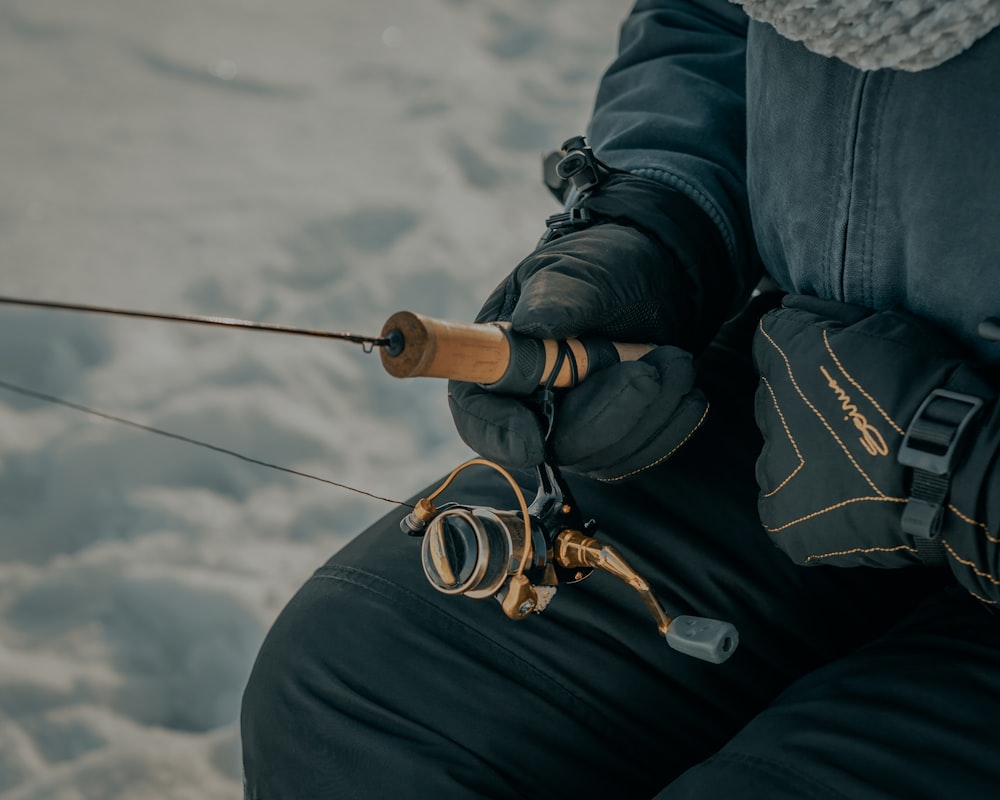 person in black jacket and black pants holding black fishing rod