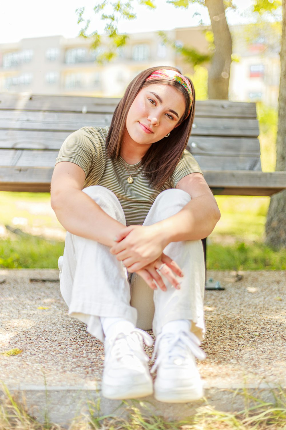 woman in gray shirt and white pants sitting on brown wooden bench