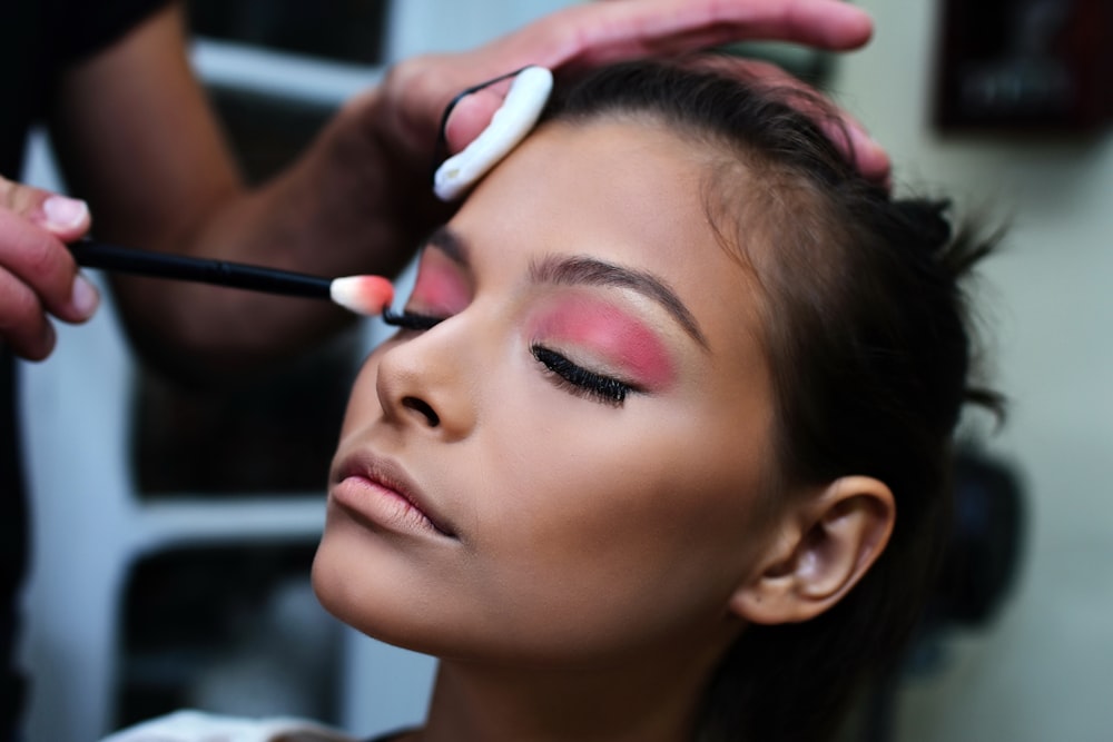 Femme avec du rouge à lèvres rose tenant une brosse à dents blanche et violette