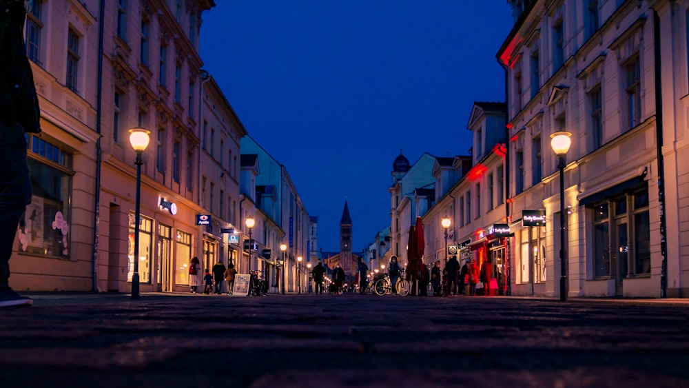 people walking on street between buildings during night time