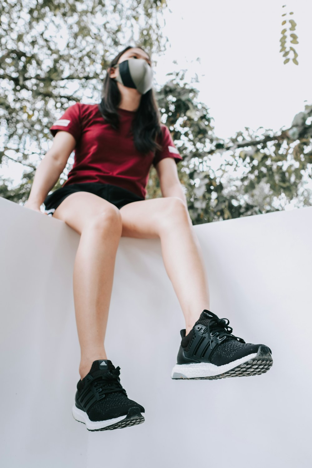 woman in red shirt and black shorts sitting on white couch