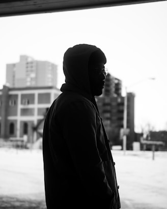 A sleek black hoodie hanging against a cityscape backdrop at dusk.