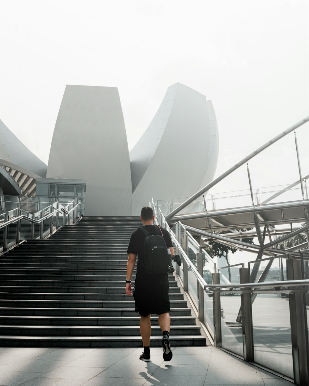 man in black jacket and black pants walking on gray concrete stairs