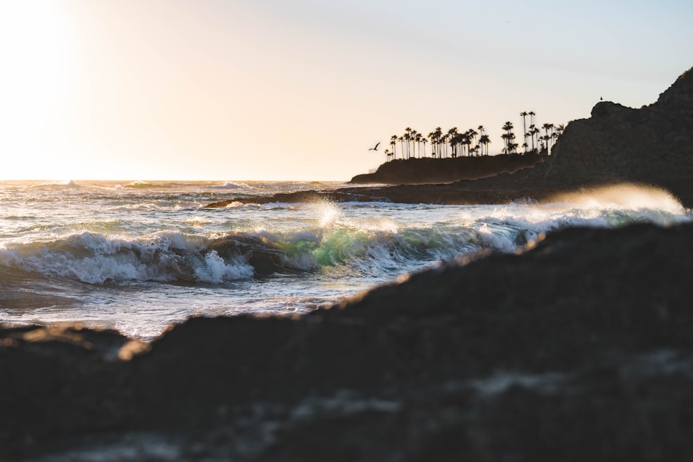 ocean waves crashing on shore during sunset