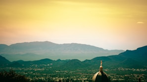 A panoramic landscape of the Himalayas with a temple in the foreground.