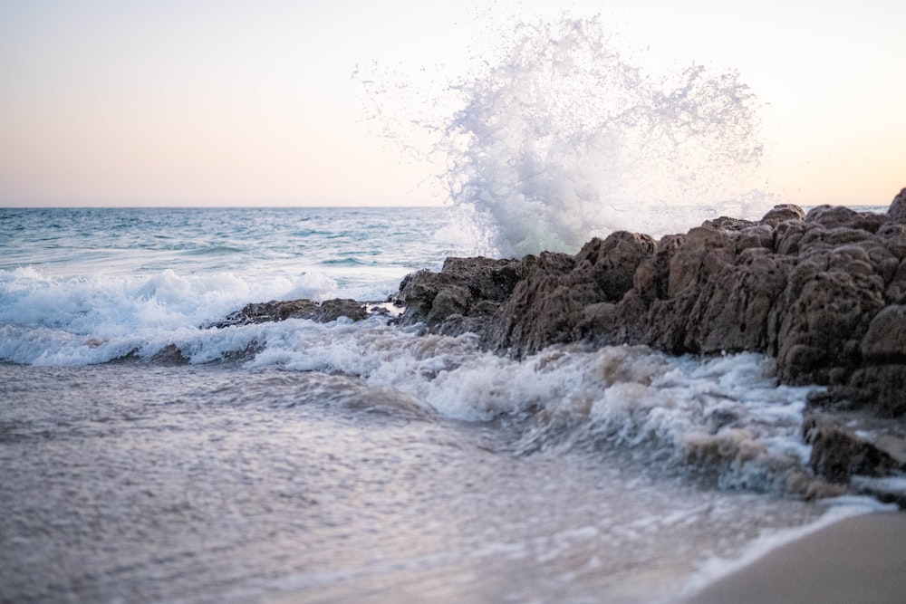 ocean waves crashing on brown rock formation during daytime