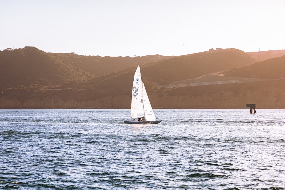 sailboat on sea near mountain during daytime