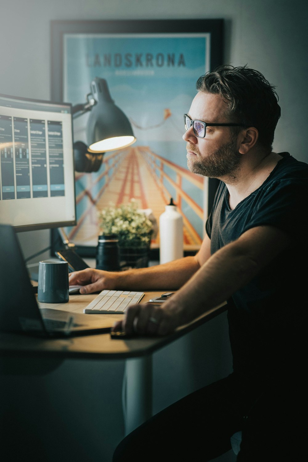 Mann in Schwarz Rundhals-T-Shirt mit schwarz gerahmter Brille am Computer