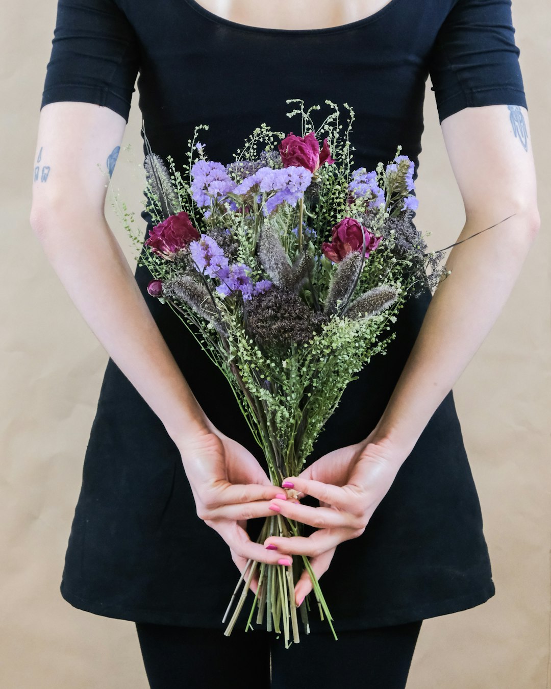 woman in black dress holding bouquet of flowers