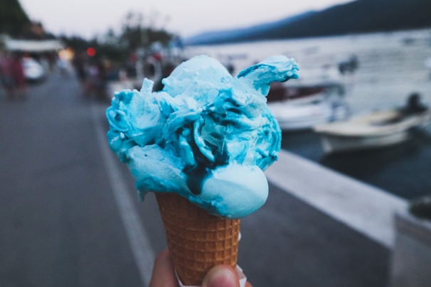 A vibrant scoop of blueberry ice cream in a waffle cone with a rustic wooden background.