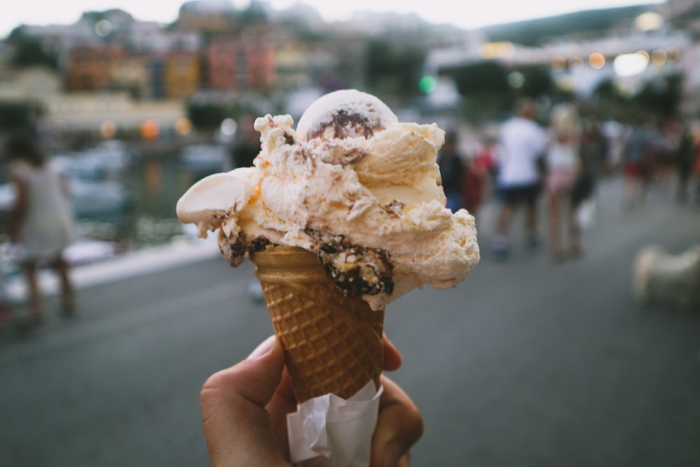 person holding ice cream cone with white ice cream