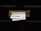 A black door with a brass mail slot containing two pieces of mail. Above the slot, a sign reads 'No Free Newspapers or Junk Mail'. The mail is protruding from the slot and includes text and images of people.