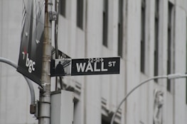A vibrant Wall Street street sign illuminated at dusk with a subtle red and gold glow.