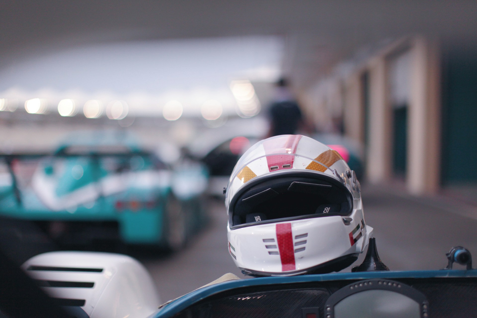 A close-up of a driver in a red and white racing suit, helmet on, ready to start the race.