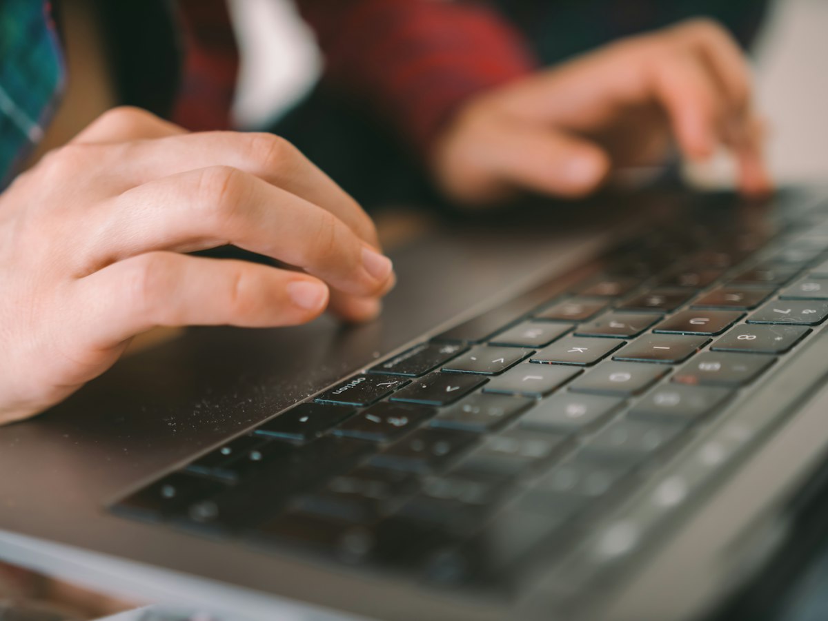 A hand resting on a black computer keyboard, showing wrist position while typing