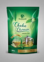 A green tea package with branding that includes images of a glass cup of tea and a glass teapot with tea in them. The packaging is predominantly green with the brand name 'Dwibhashi' and product name 'Chaha Churnam' prominently displayed. The package highlights the tea's natural, antioxidant-rich qualities, and features imagery of fresh green tea leaves.