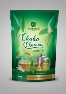 Close-up of deep gold and emerald green premium tea packaging with elegant Assam tea branding.