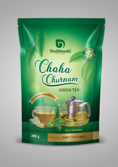A green tea package with branding that includes images of a glass cup of tea and a glass teapot with tea in them. The packaging is predominantly green with the brand name 'Dwibhashi' and product name 'Chaha Churnam' prominently displayed. The package highlights the tea's natural, antioxidant-rich qualities, and features imagery of fresh green tea leaves.
