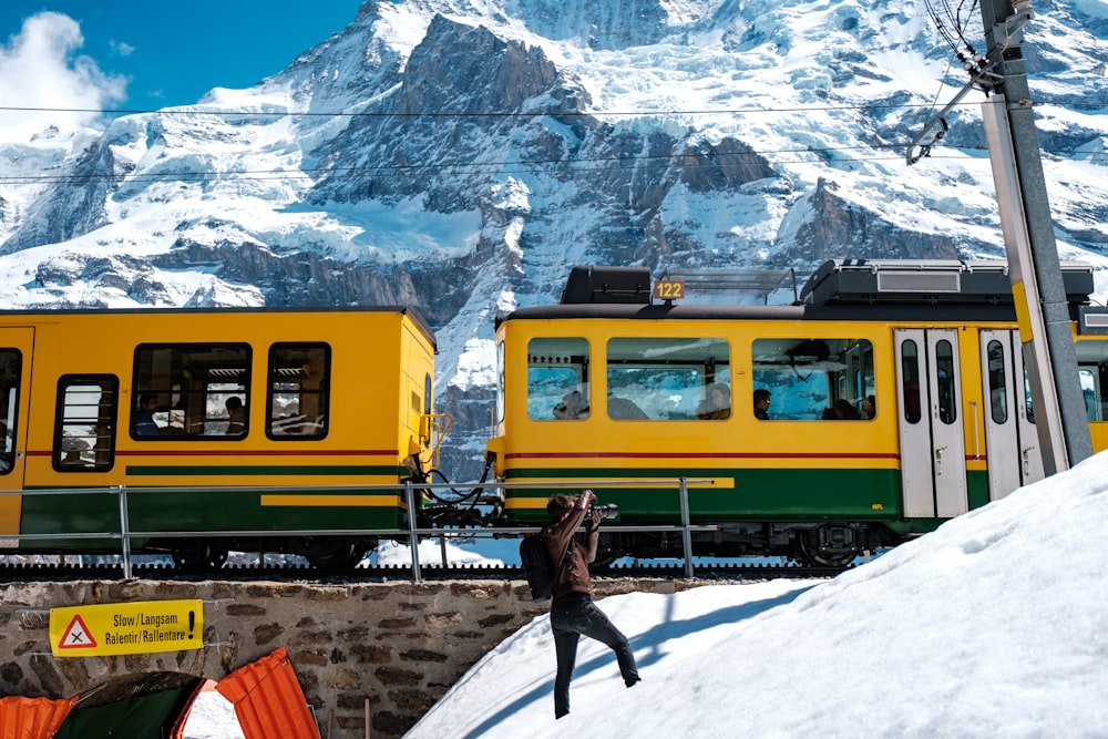 person in black jacket standing near yellow train during daytime