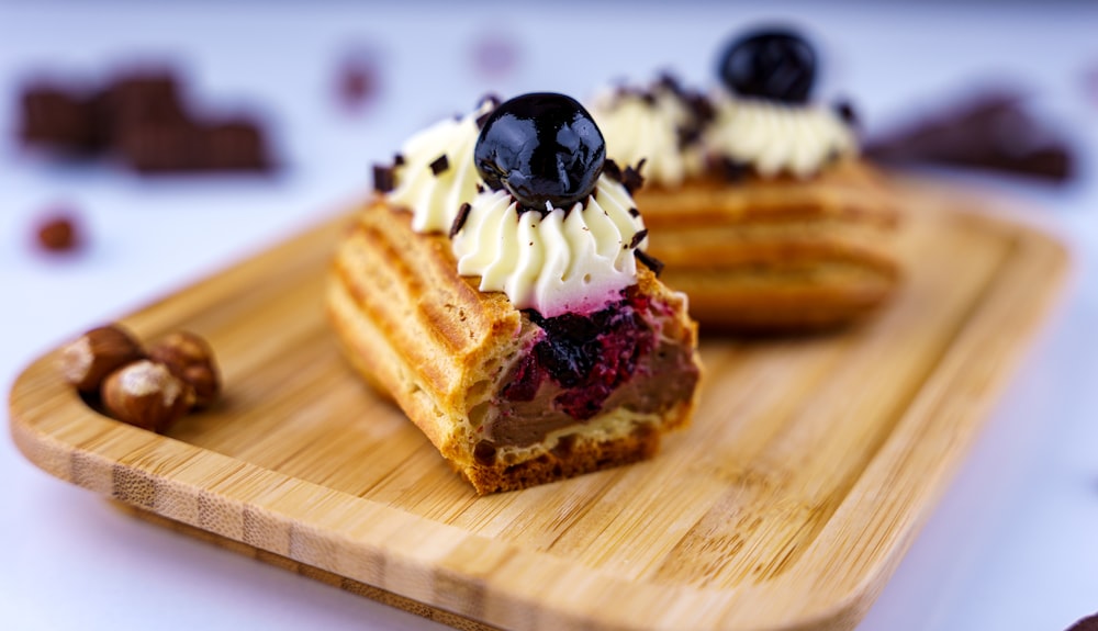 sliced bread with white icing and black berries on brown wooden chopping board