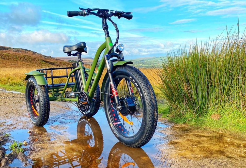 Bicicleta verde y negra sobre arena marrón durante el día