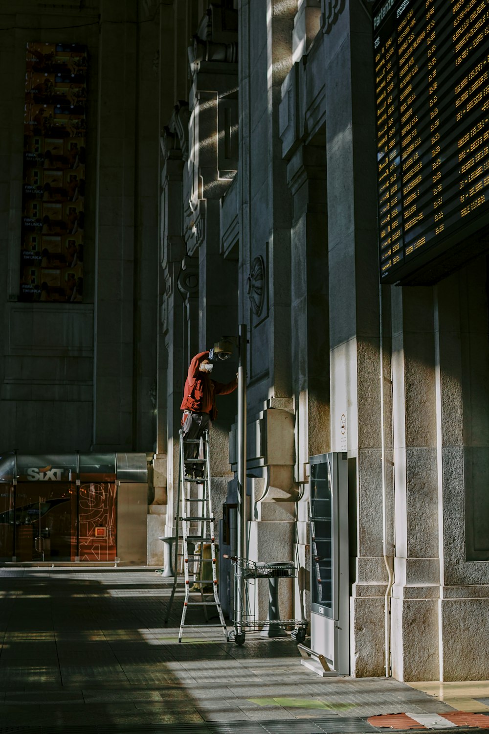 Hombre con chaqueta roja y pantalones negros de pie sobre el suelo de hormigón gris