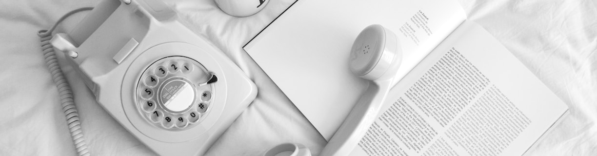 white rotary phone beside white ceramic mug