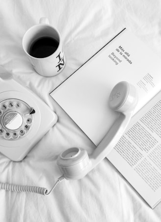 white rotary phone beside white ceramic mug