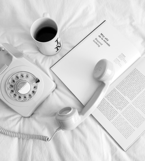 white rotary phone beside white ceramic mug