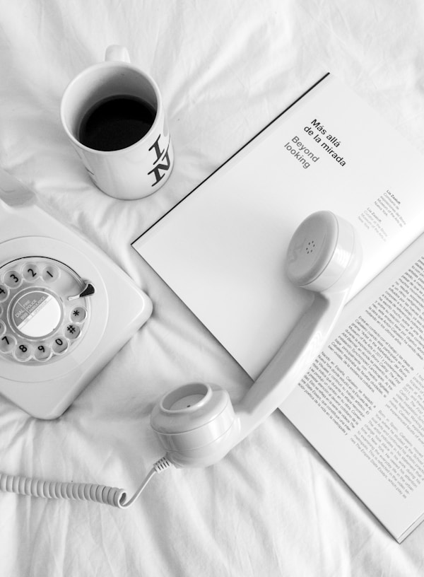 white rotary phone beside white ceramic mug